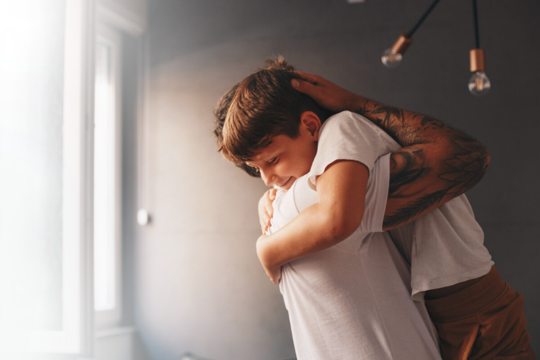 Father with tattoos embraces son in hug